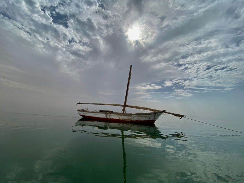 A lonely artisan fishing boat floats in still water.
