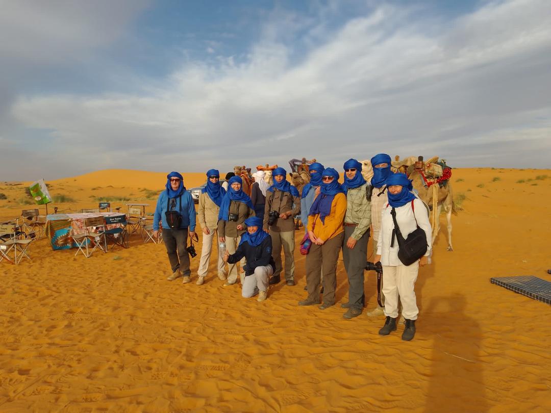 A tour group poses in front of an expansive desert