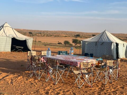 A large campsite is shown with nomadic tents, where a table is set ready for guests