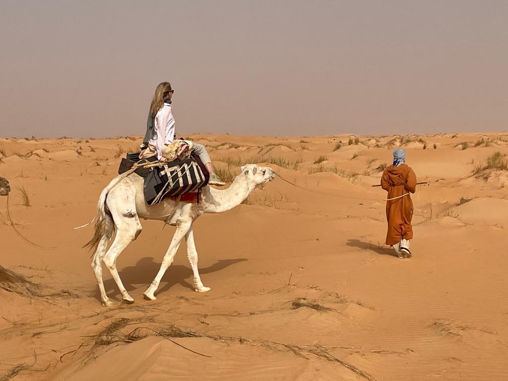 A woman rides a camel lead by a tour guide
