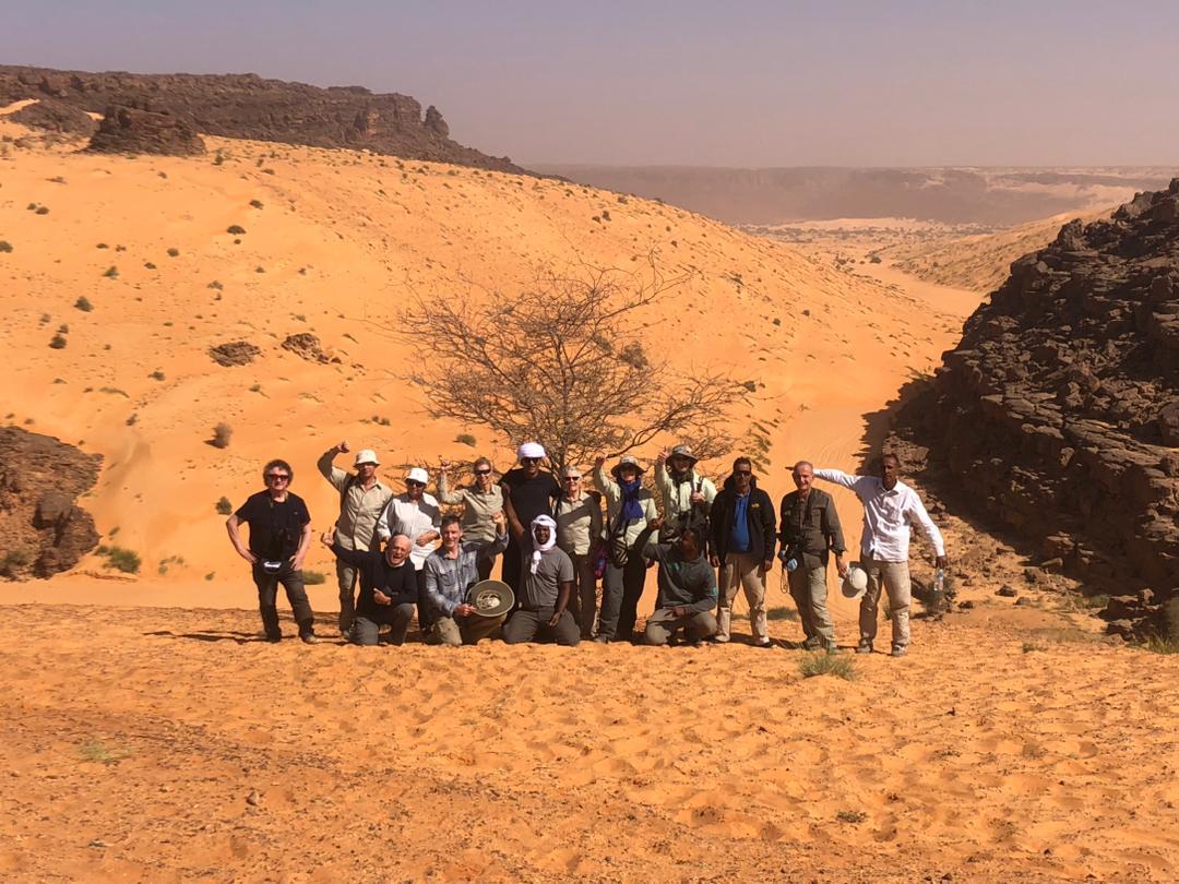 A tour group poses in rocky desert
